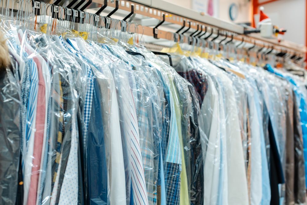 A row of clothes hanging on a rack in a dry cleaner.