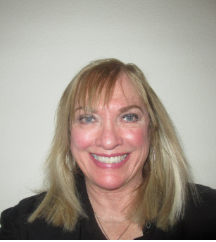 A woman with blonde hair and blue eyes is smiling for the camera