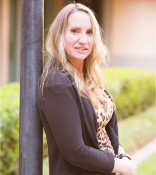 A woman leaning against a pole with a smile on her face