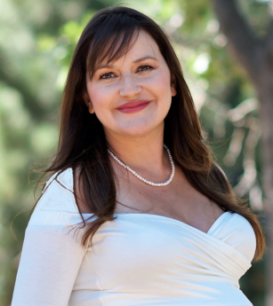 A pregnant woman wearing a white top and a pearl necklace