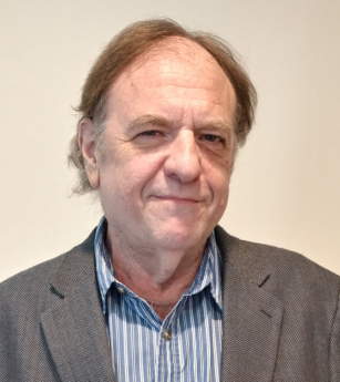A man in a suit and striped shirt smiles for the camera