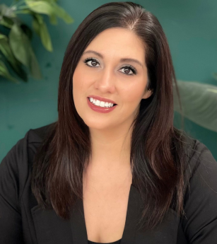 A woman in a black jacket is smiling for the camera