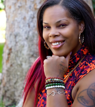 A woman with red hair has a tattoo on her arm that says i love you