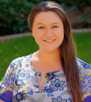 A woman wearing a blue and yellow floral shirt smiles for the camera