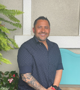 A man with a tattoo on his arm is sitting on a bench.