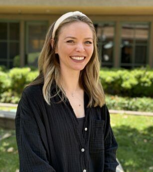 A woman wearing a headband and a black shirt is smiling for the camera.