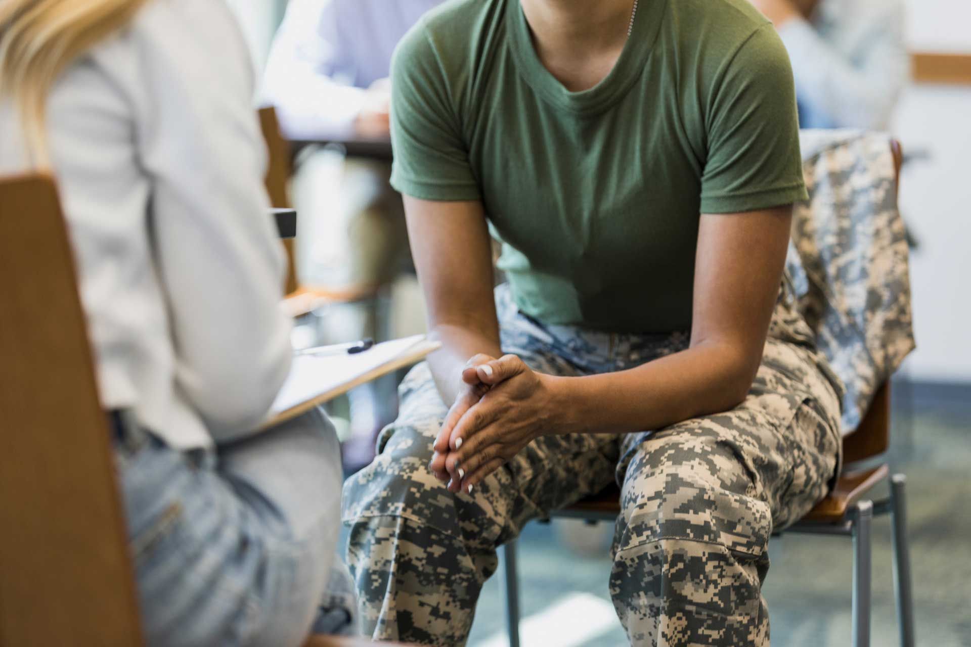 A soldier is sitting in a chair talking to a doctor.