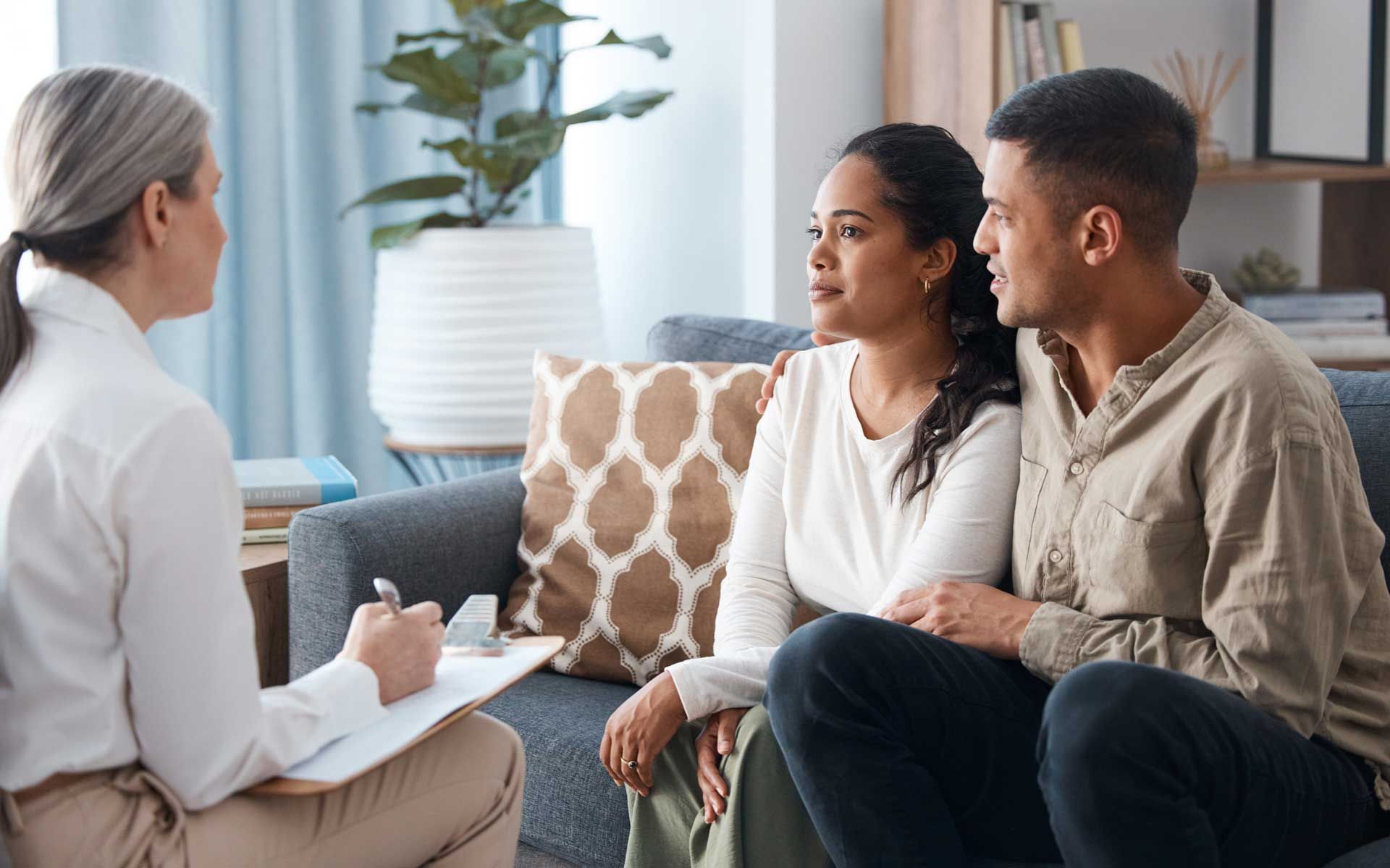 A man and a woman are sitting on a couch talking to a woman.