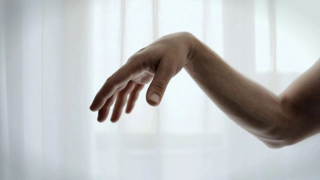 A close up of a woman 's hand reaching out towards a window.