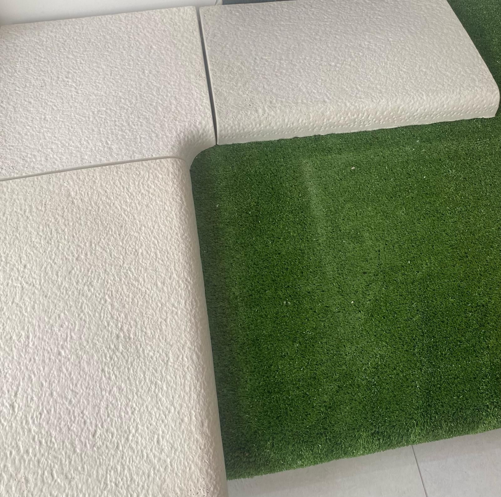 Un cuscino bianco e un cuscino verde sono appoggiati uno accanto all'altro su un pavimento piastrellato.