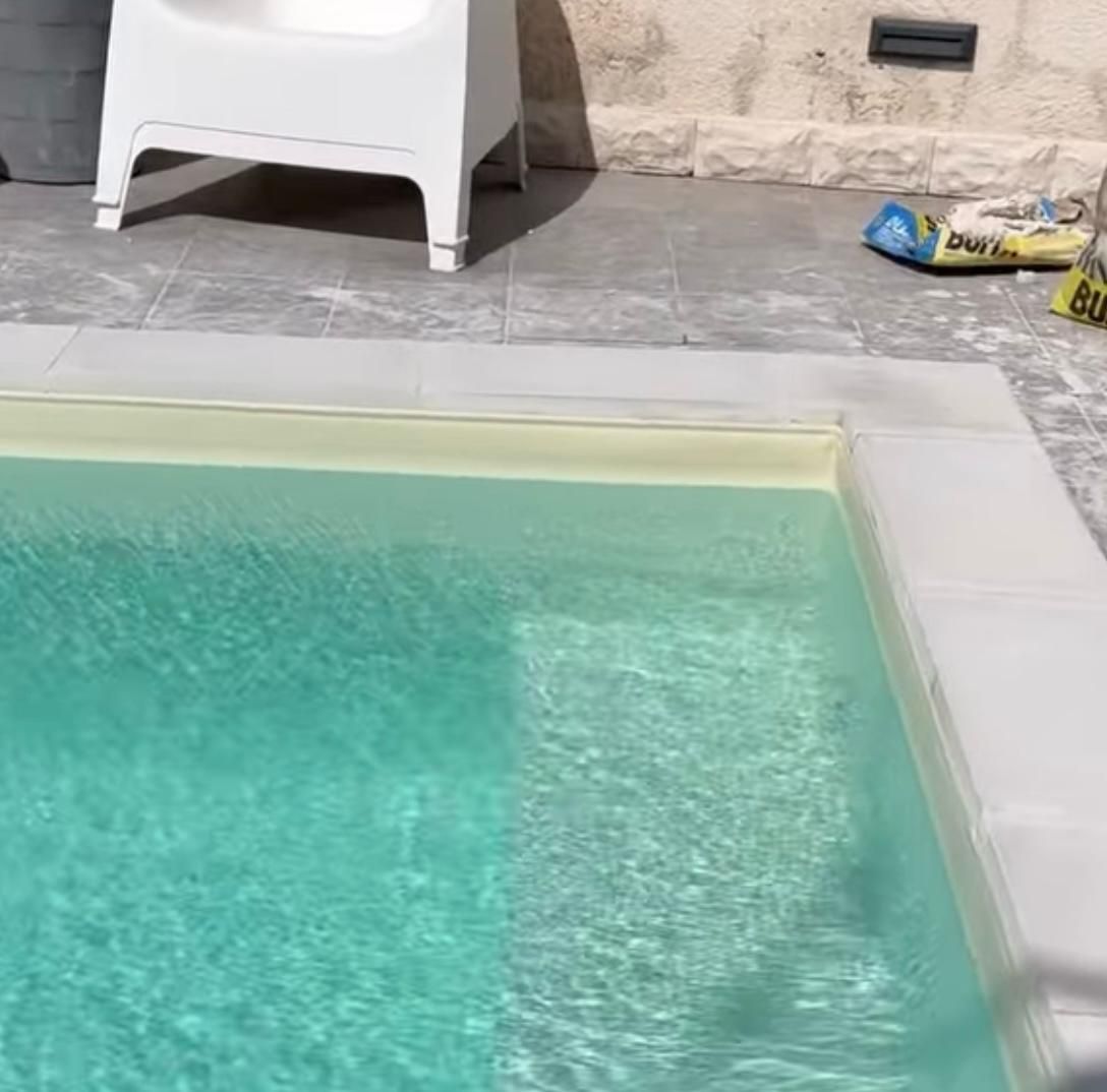 Una piscina con una sedia e un sacchetto di salviette sul bordo.