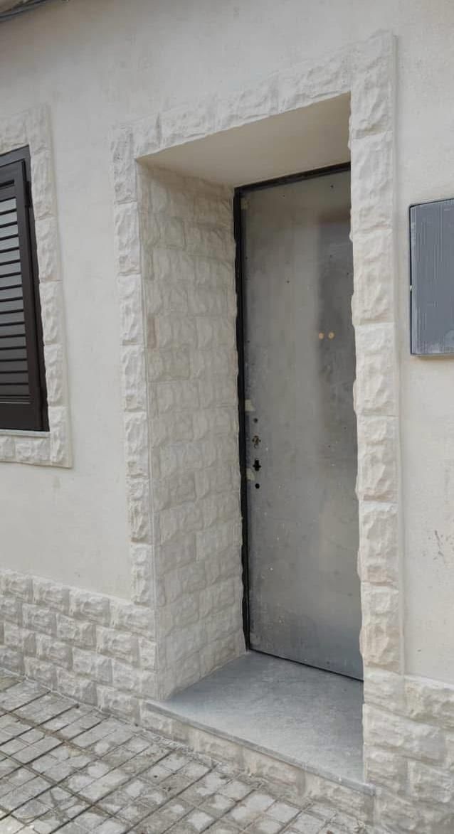 La porta d'ingresso di una casa con una porta in acciaio inossidabile e un muro in pietra.