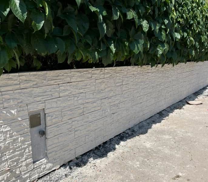 Un muro di mattoni bianchi con foglie verdi dietro