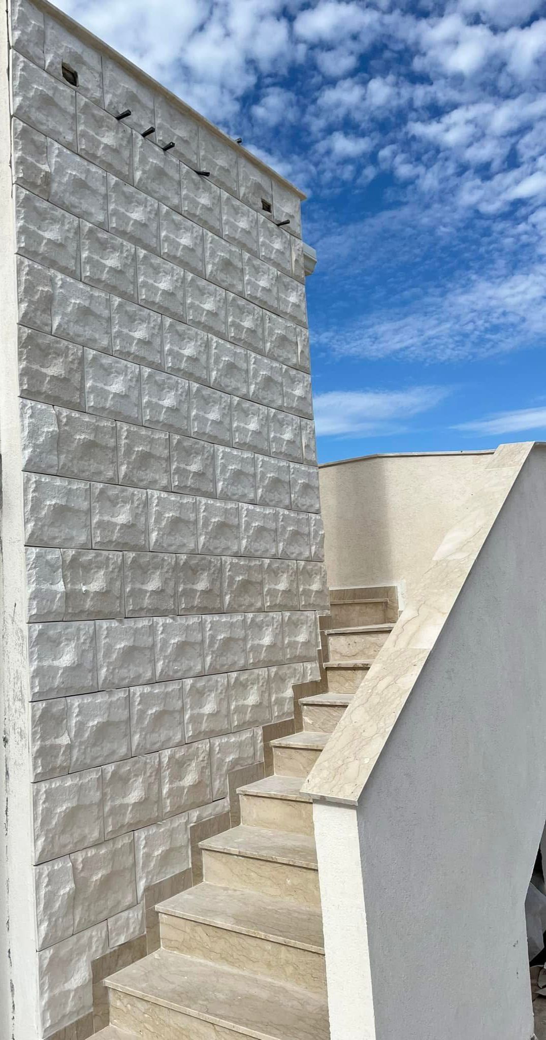 Un muro di mattoni bianchi con delle scale che portano ad esso.