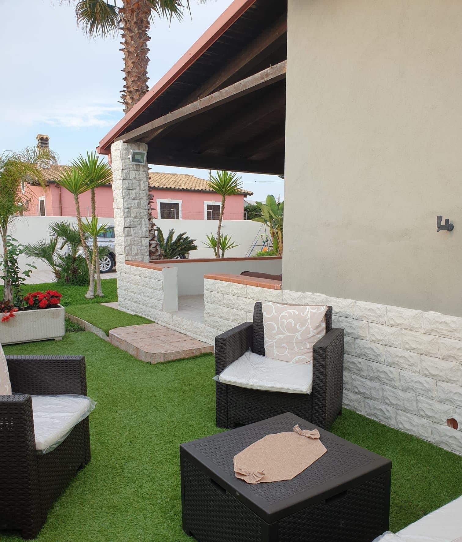 Un patio con sedie e un tavolo davanti a una casa