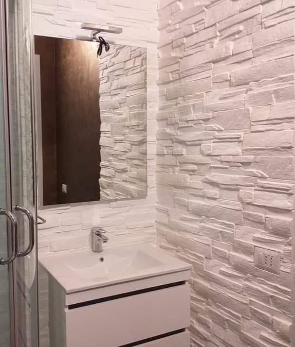 Un bagno con lavandino, specchio e box doccia.