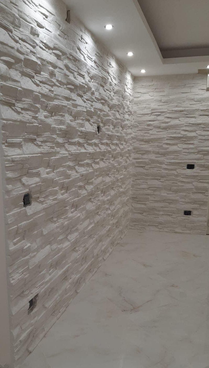 Una stanza con un muro di mattoni e un pavimento bianco.