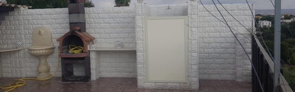 Un muro di mattoni con un lavandino e un barbecue sopra.