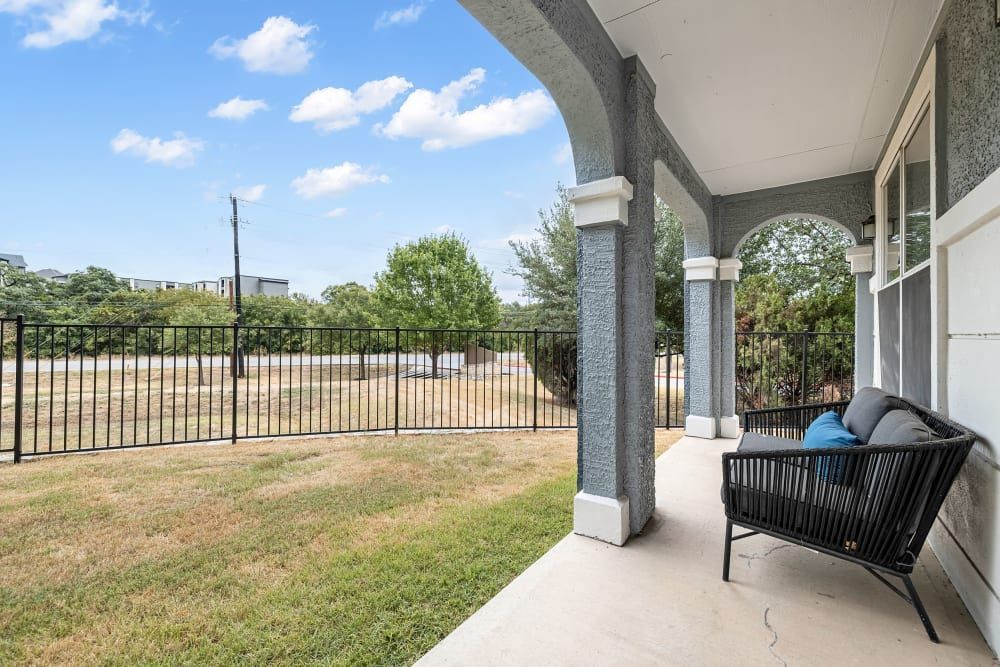 a porch with a couch and a fence in the background at Marquis at Crown Ridge in San Antonio, TX.
