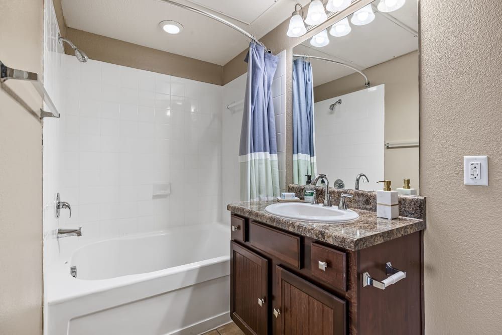 a bathroom with a sink, tub, and mirror at Marquis at Crown Ridge in San Antonio, TX.