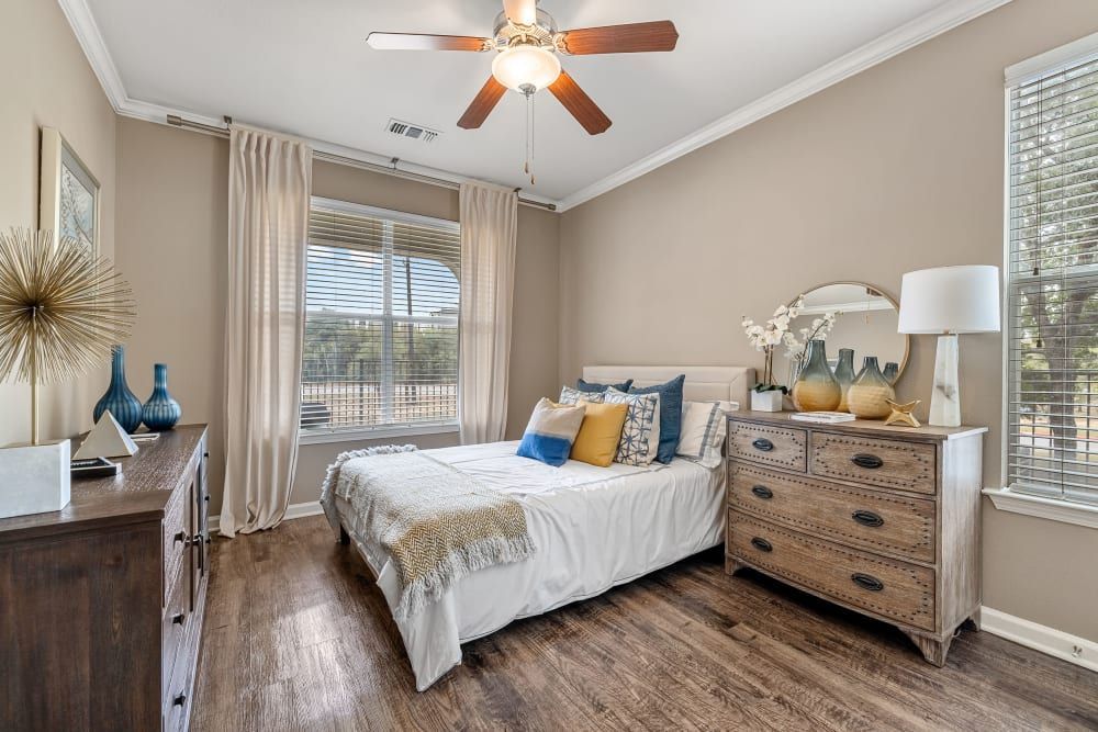 a bedroom with a bed, dresser, and ceiling fan at Marquis at Crown Ridge in San Antonio, TX.
