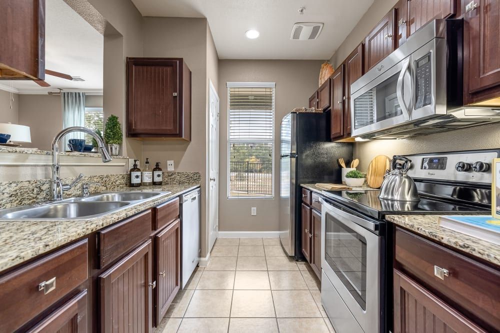 a kitchen with stainless steel appliances and wooden cabinets at Marquis at Crown Ridge in San Antonio, TX.