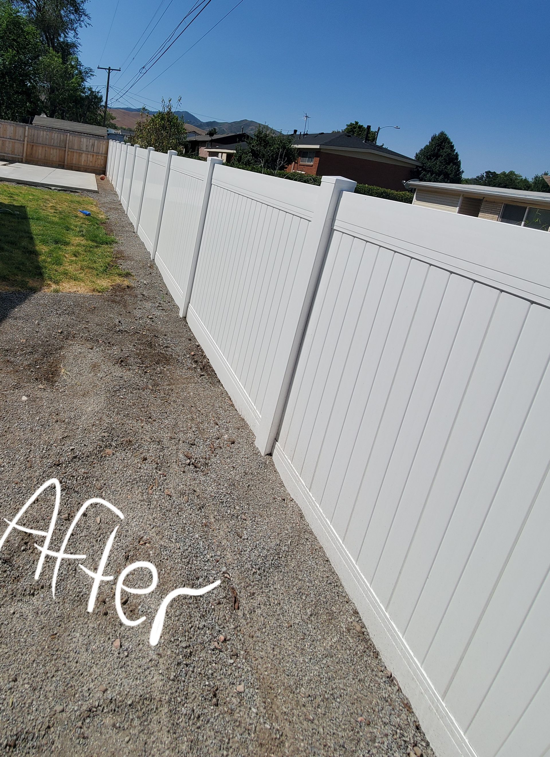 A white fence is sitting on top of a gravel driveway.