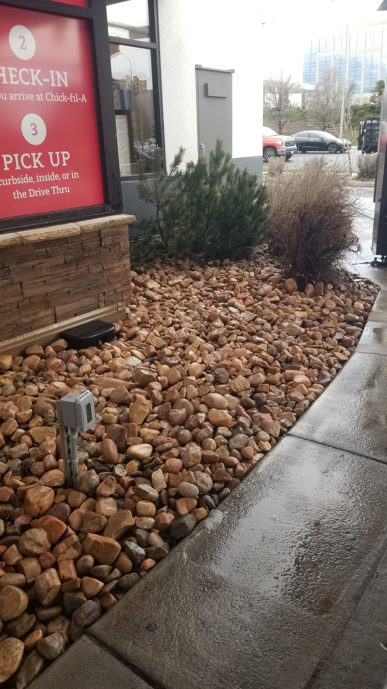 A person is standing on a sidewalk in front of a chick fil a restaurant.