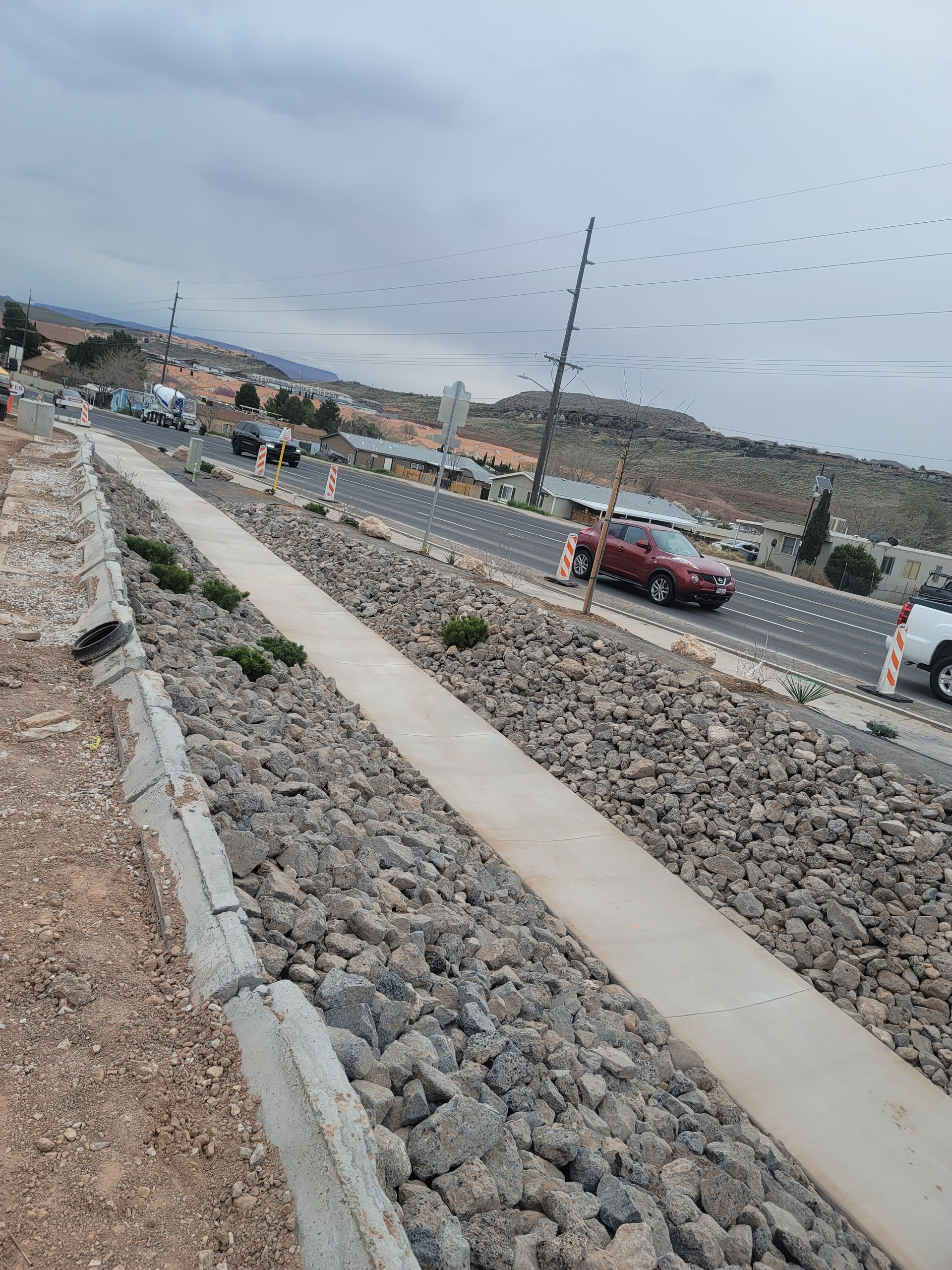 A red car is parked on the side of the road next to a sidewalk.