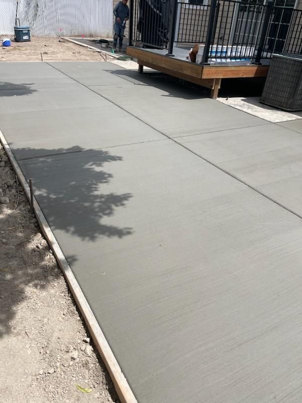 A concrete walkway is being built next to a deck.