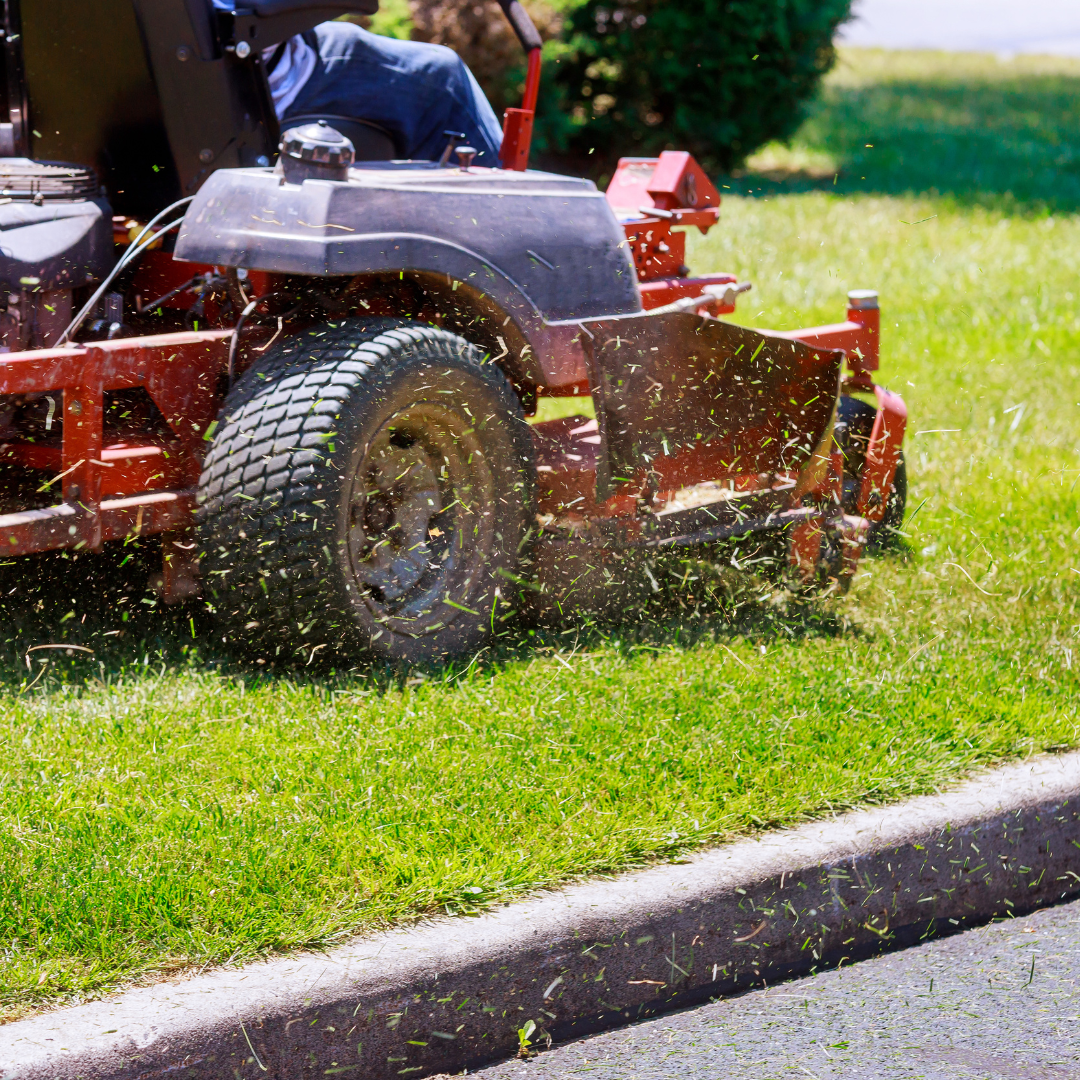 A man is riding a lawn mower on a lush green lawn.