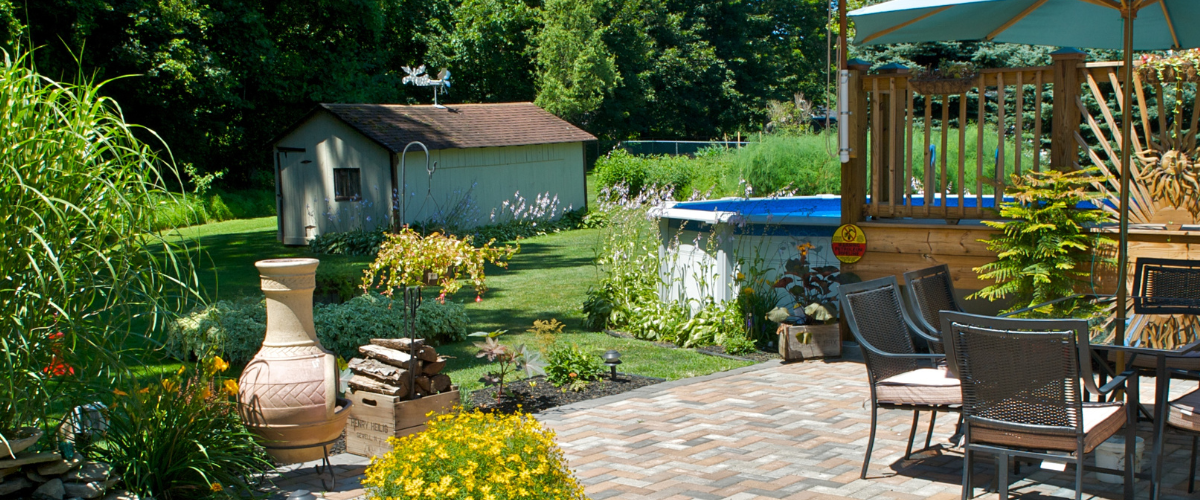 A patio with a table and chairs and a pool in the background.