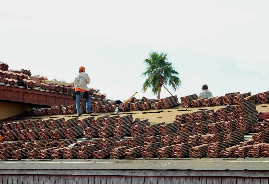 Two men are working on the roof of a building.