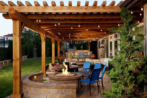 Wooden pergola over a patio with a fire pit, seating, and string lights.