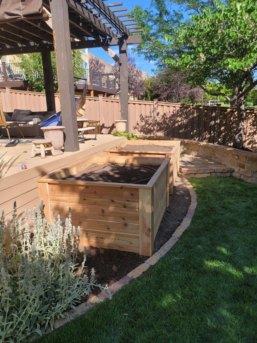A wooden planter is sitting in the middle of a lush green yard.