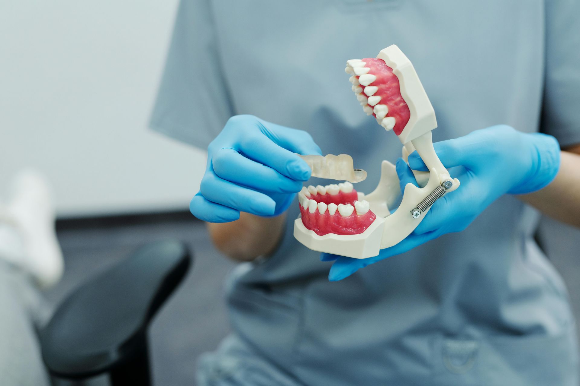 Dental assistant holding a model of teeth, showing how a retainer works and how it helps