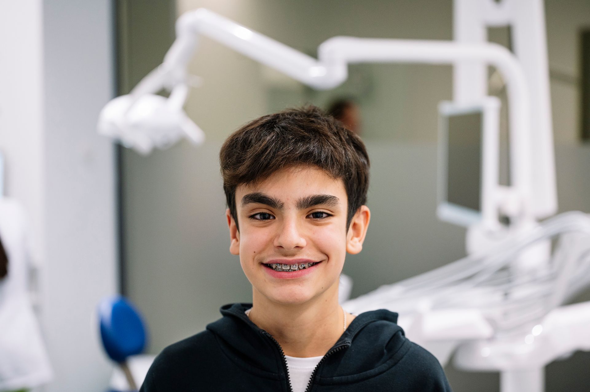 Smiling person in a dental clinic, with dental equipment blurred in the background