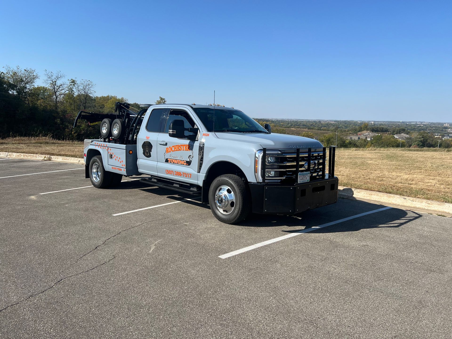 Silver car being loaded onto a blue tow truck with a striped warning panel.