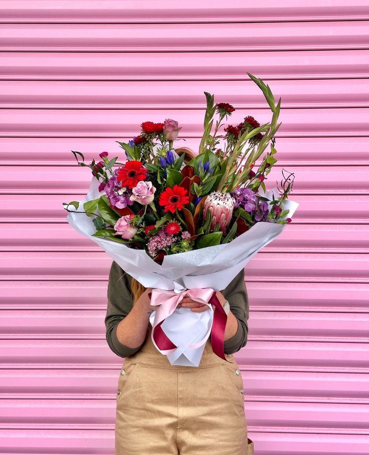 Een vrouw houdt een groot boeket bloemen voor haar gezicht.