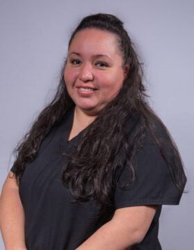 A woman in a black scrub top is smiling for the camera.