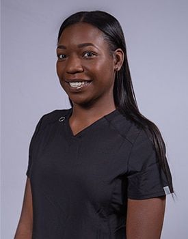 A woman in a black scrub top is smiling for the camera.