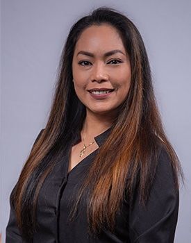 A woman with long hair is wearing a black shirt and smiling for the camera.