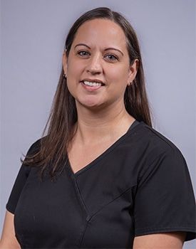 A woman in a black scrub top is smiling for the camera.