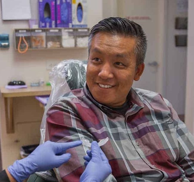 A man is sitting in a dental chair being examined by a dentist.