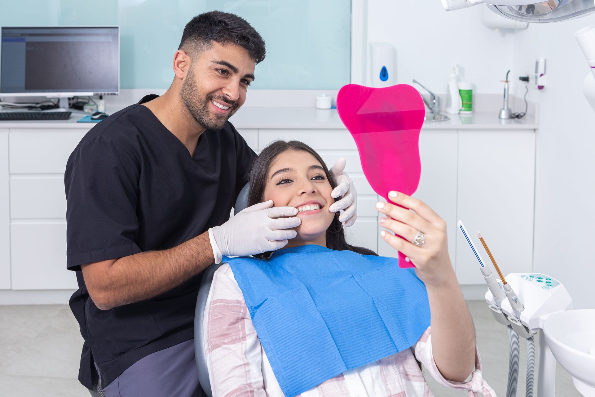 Dentist shows patient a mirror, evaluating teeth. Dental office.