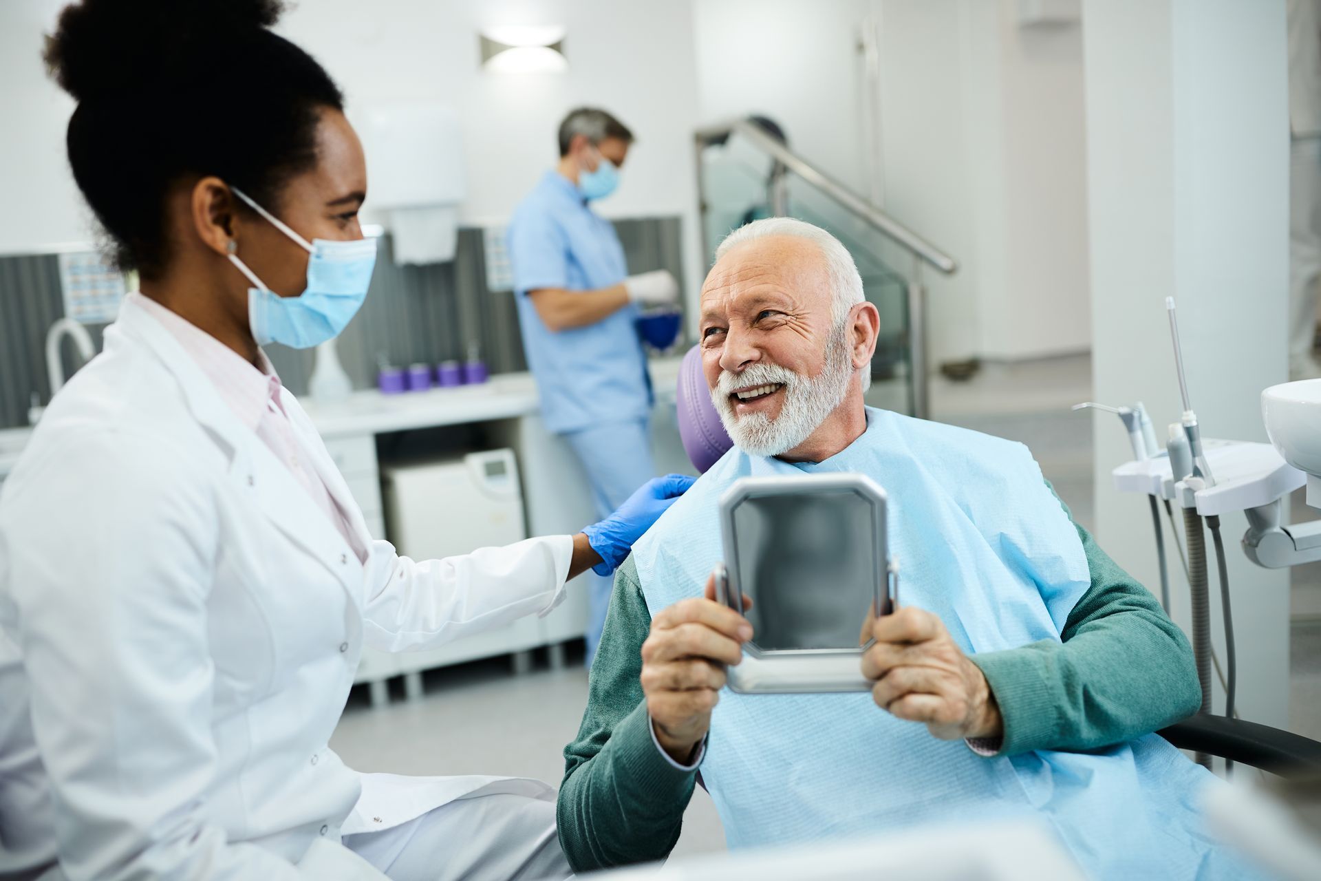 Dentist showing smiling patient their teeth with a mirror in a dental office.