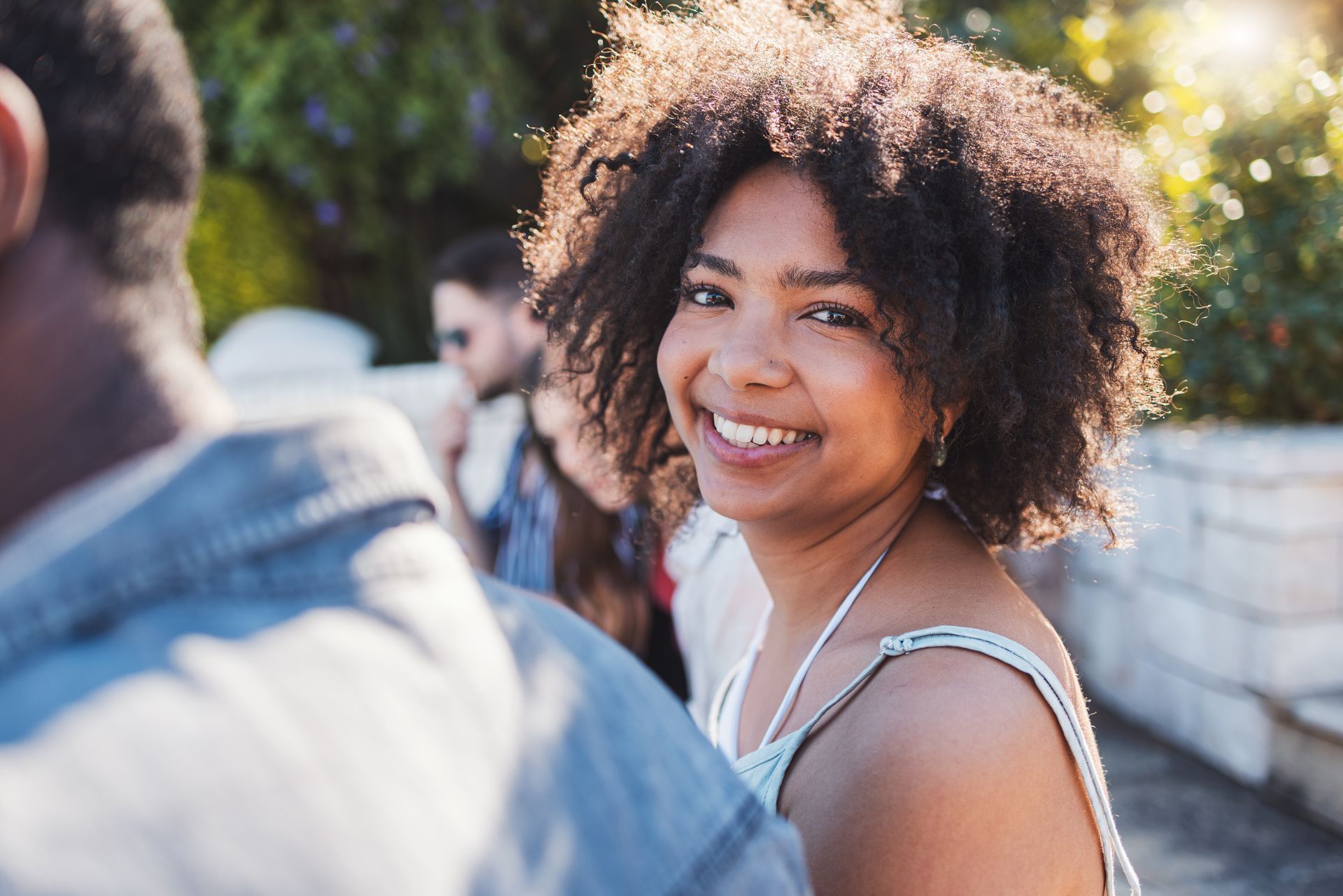 A woman with curly hair is smiling while standing next to a man.