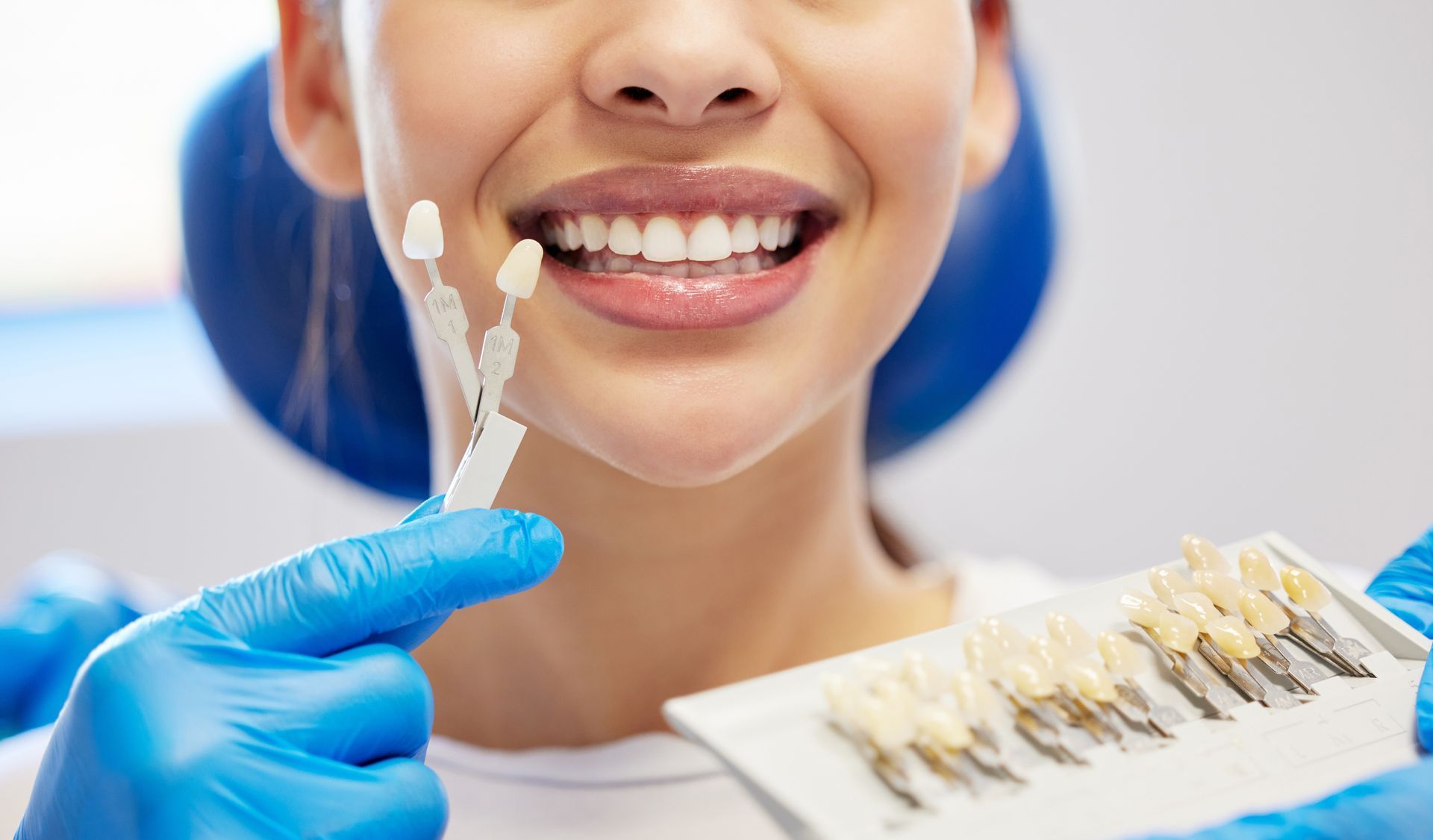 Dental technician showing a tooth shade guide to a smiling patient in a clinic