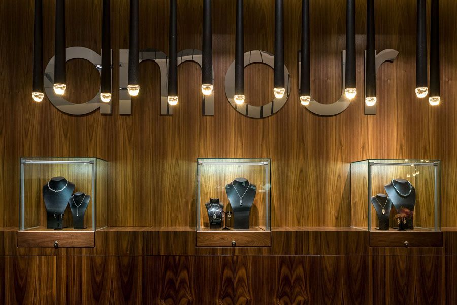 A jewelry store with a wooden wall and display cases filled with jewelry.
