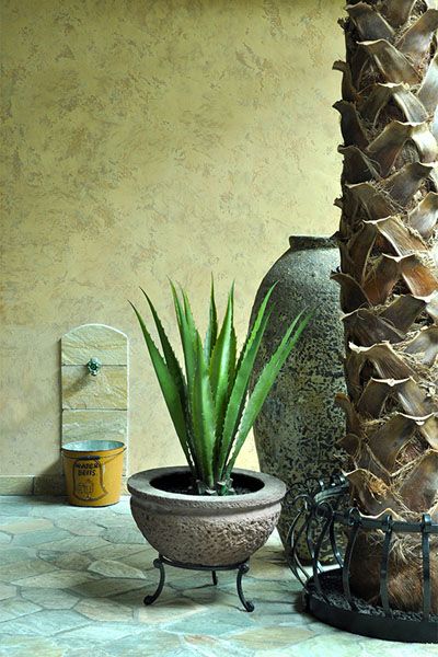 A potted plant is sitting on a tiled floor next to a palm tree.